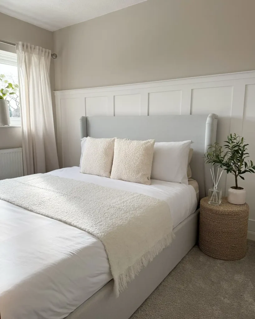 Neutral guest bedroom with soft bedding, wicker nightstand, and potted plant.
