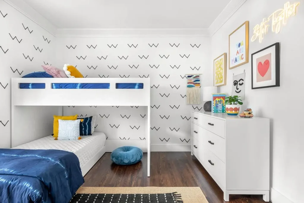 Boy and girl shared bedroom with white bunk beds, graphic wallpaper, and colorful accents.