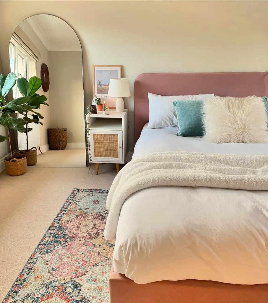 Full length mirror in bedroom with arched frame beside pink bed and layered rug.