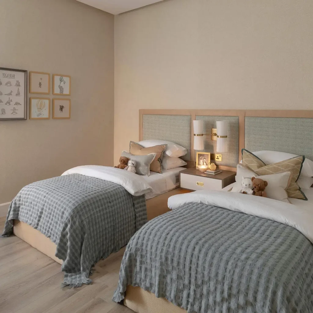 Elegant boy and girl shared bedroom with neutral bedding, soft lighting, and plush décor.