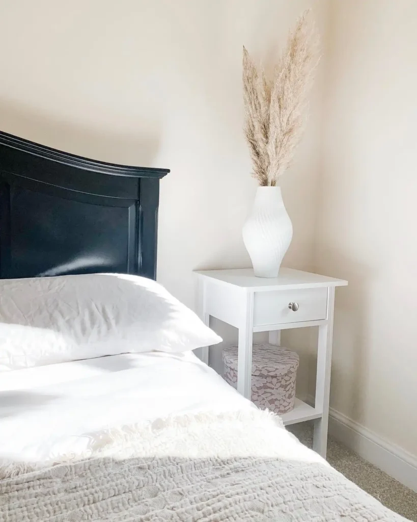 Guest bedroom with black headboard, white side table, and pampas grass décor.