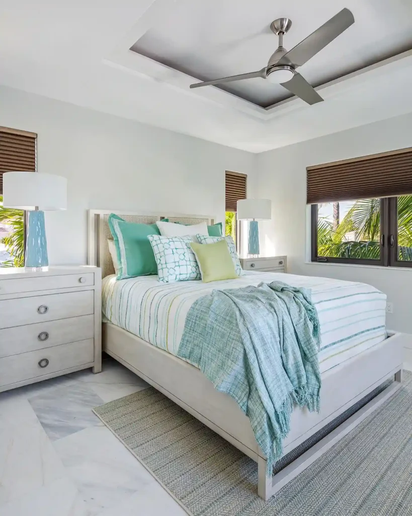 bedding with striped quilt, teal pillows, and light wood furniture.
