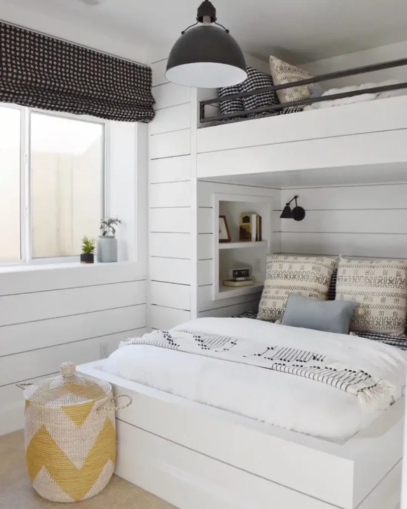 white iron bed, blue bedding, and round wall mirror.