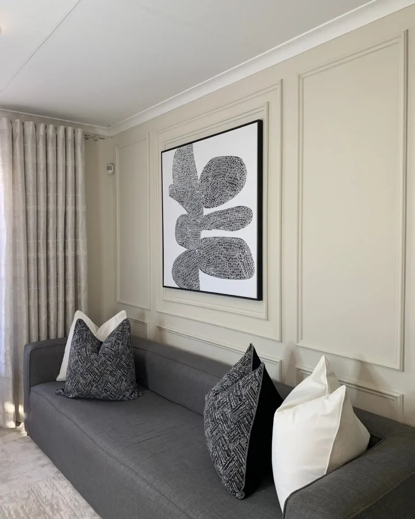 Modern living room with gray sofa and large abstract black-and-white wall art above couch.
