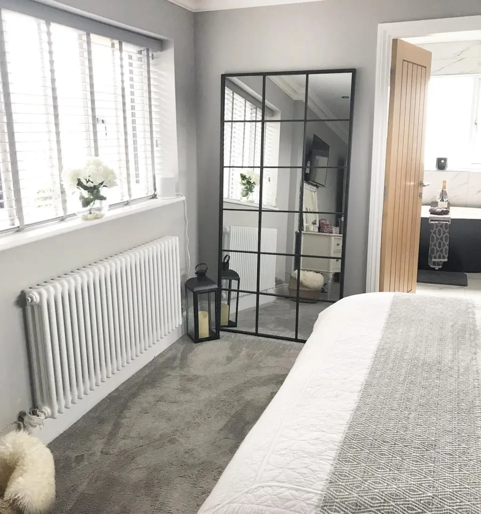 Black grid-style full length mirror in bedroom with gray décor and lanterns.