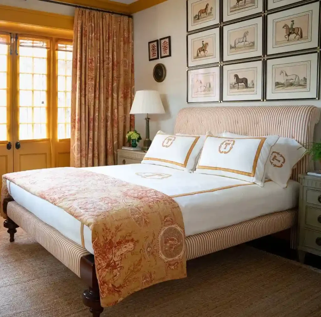 Guest bedroom bedding in golden hues with monogrammed pillows and striped headboard.