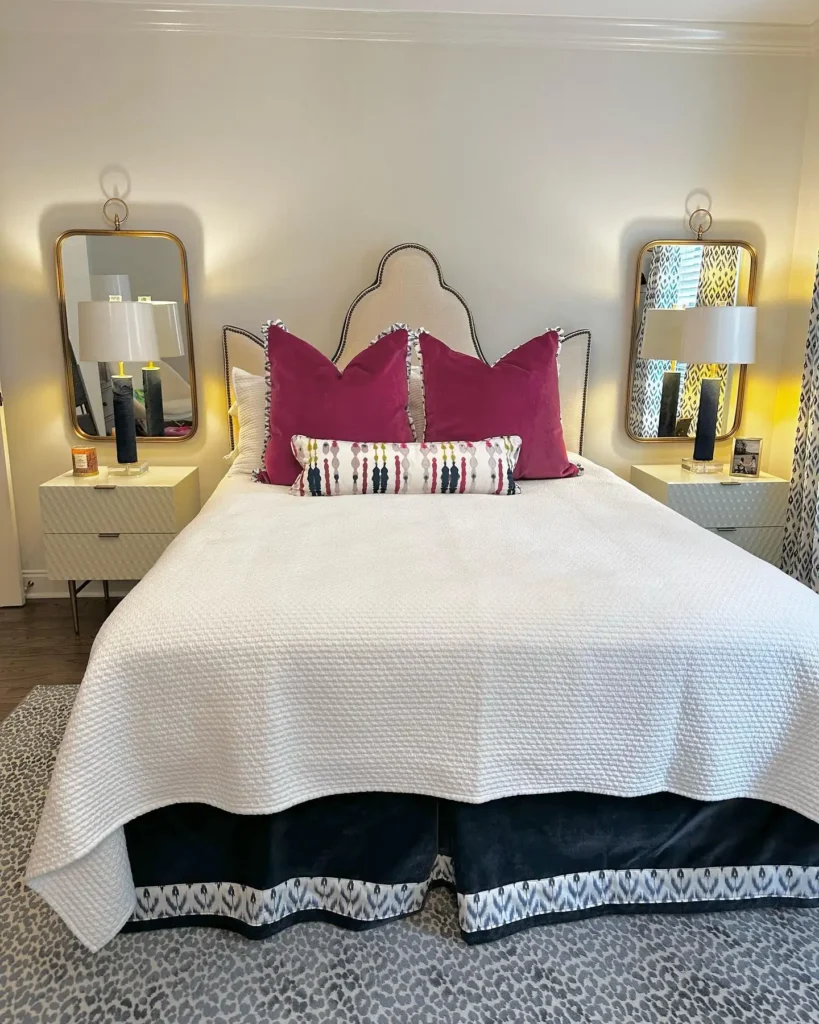  Preteen girls bedroom featuring bold magenta pillows, modern mirrors, and neutral bedding with patterned accents.
