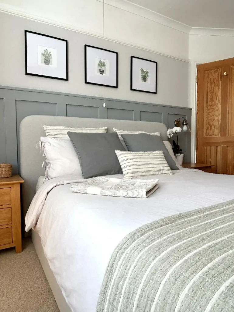 Guest bedroom idea on a budget with grey paneled wall, neutral bedding, and wooden side tables.