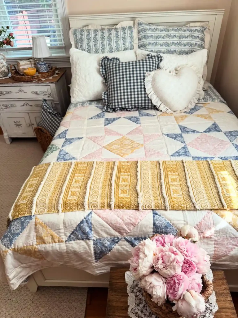 Guest bedroom bedding with colorful quilt, patterned pillows, and rustic accents.
