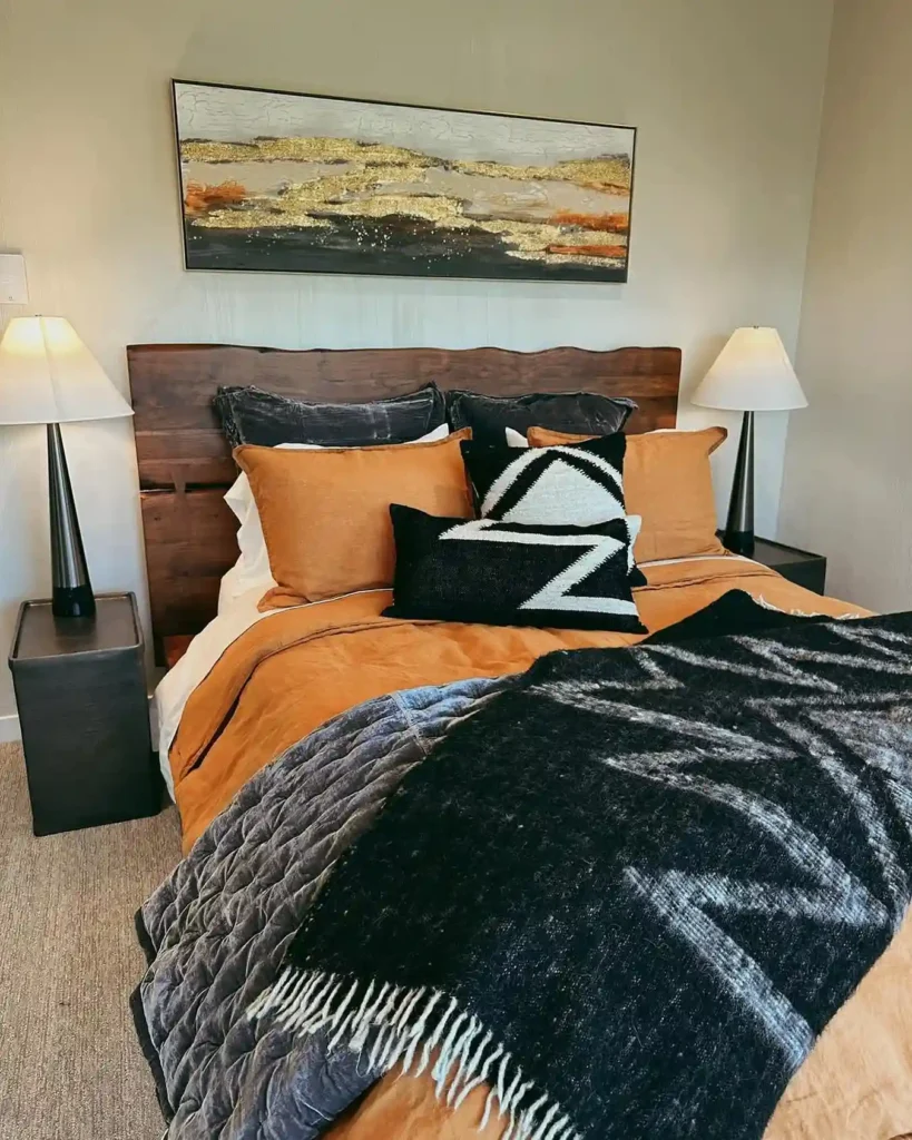 Guest bedroom bedding with rust-orange duvet, black throw, and bold patterned pillows.
