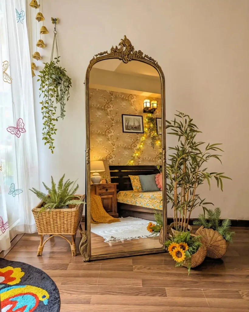 Gold ornate full length mirror in bedroom with plants and fairy lights.