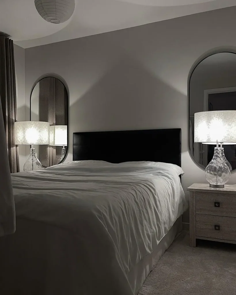 Guest bedroom idea on a budget with arched mirrors, glass lamps, and black headboard.