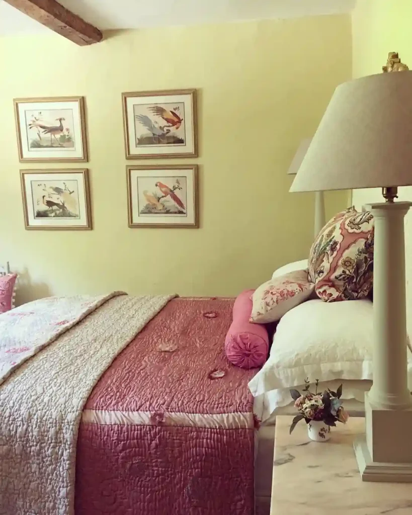 Guest bedroom bedding with pink quilt, floral pillows, and framed bird artwork.