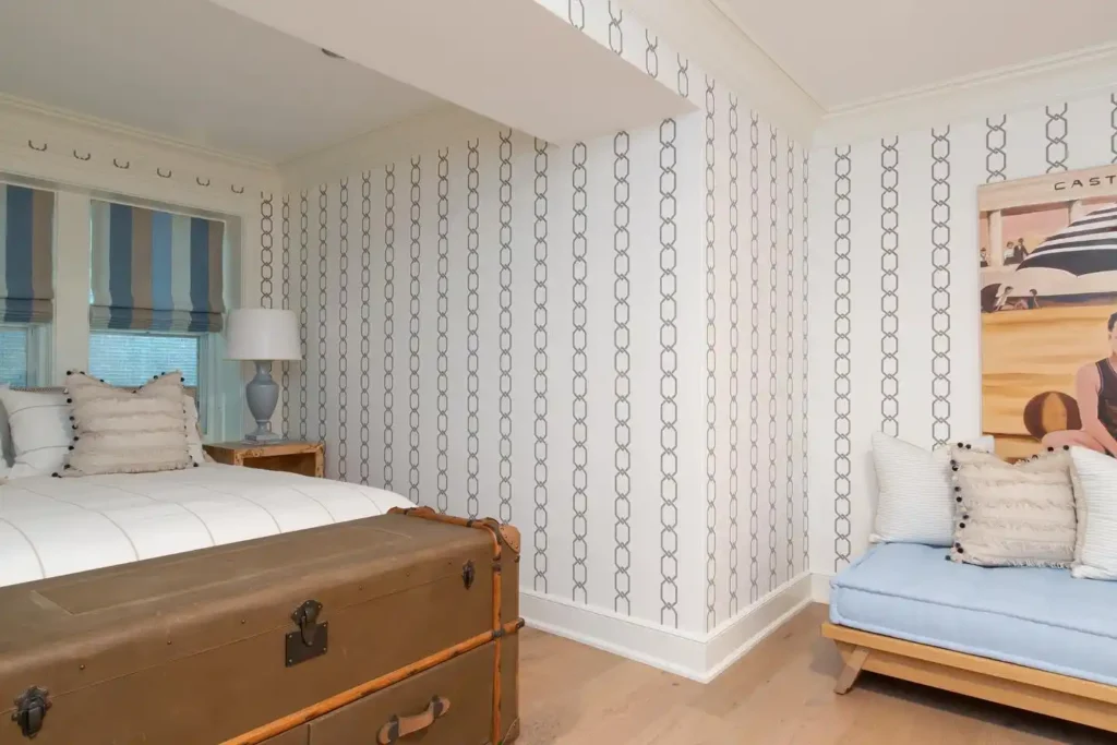 bedroom with patterned wallpaper, striped shades, and vintage trunk.