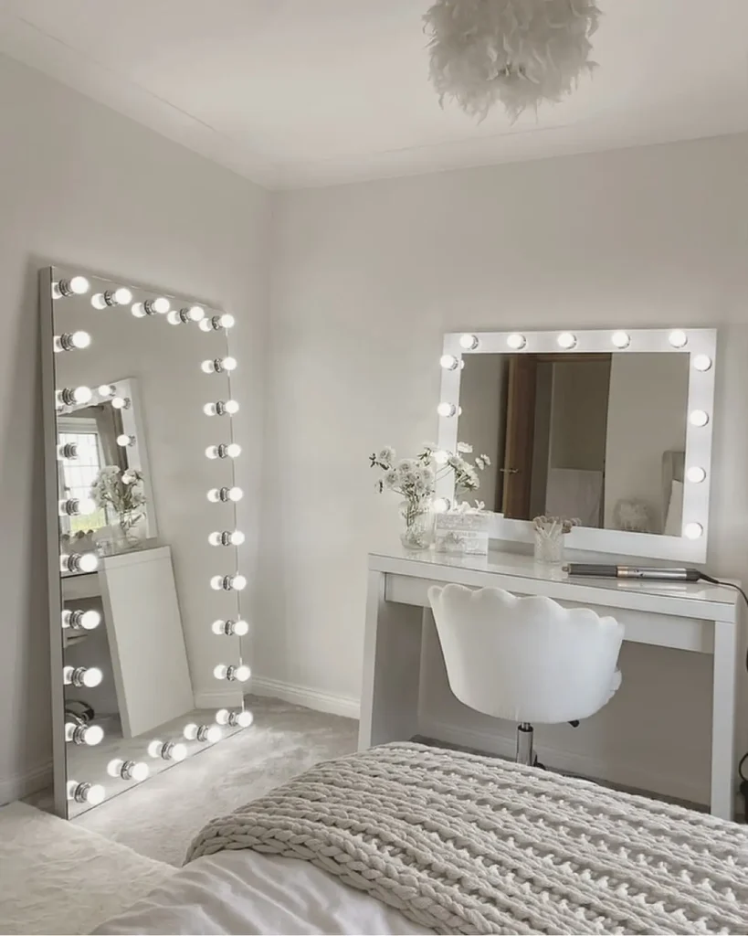Full length mirror in bedroom framed with Hollywood-style bulbs beside vanity desk.