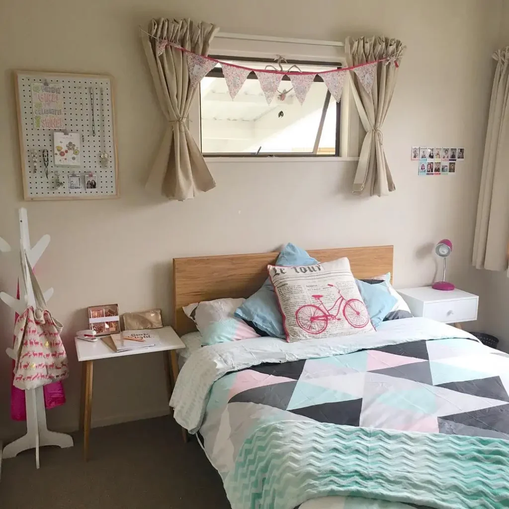 Minimal preteen girls bedroom with pegboard wall, pastel bedding, bunting decor, and neutral walls.
