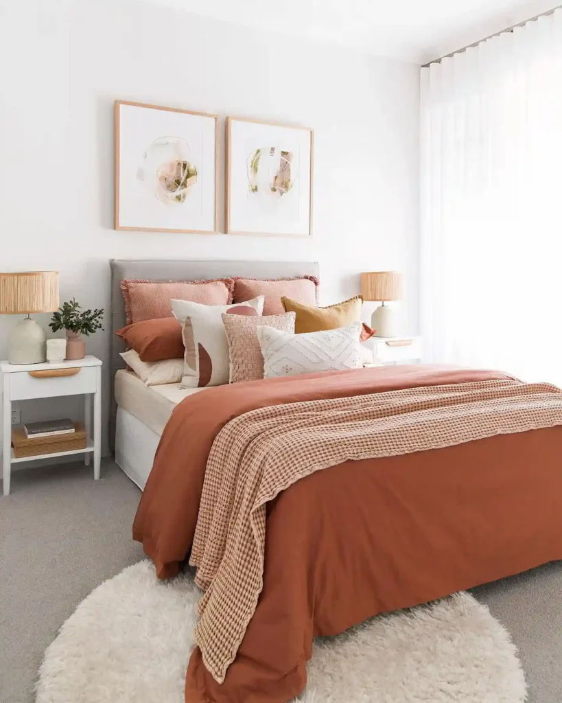 Guest bedroom bedding in terracotta and blush tones with layered throws and pillows.
