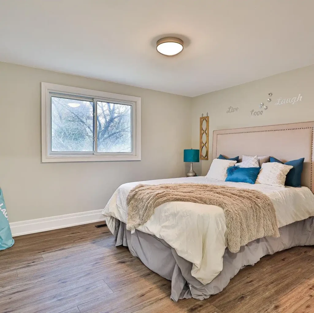 bedroom with beige walls, teal accent pillows, and cozy bedding.