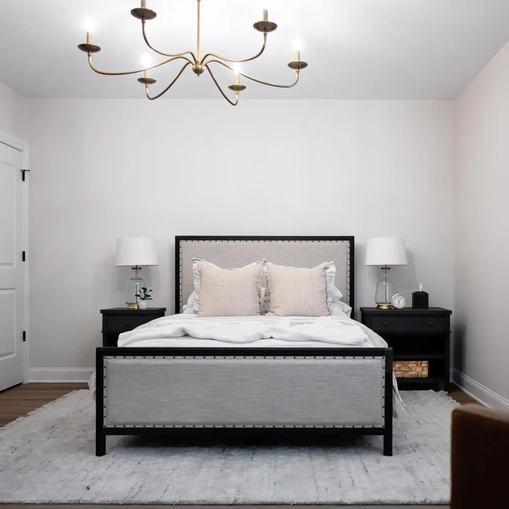 black bed frame, beige pillows, and statement chandelier.