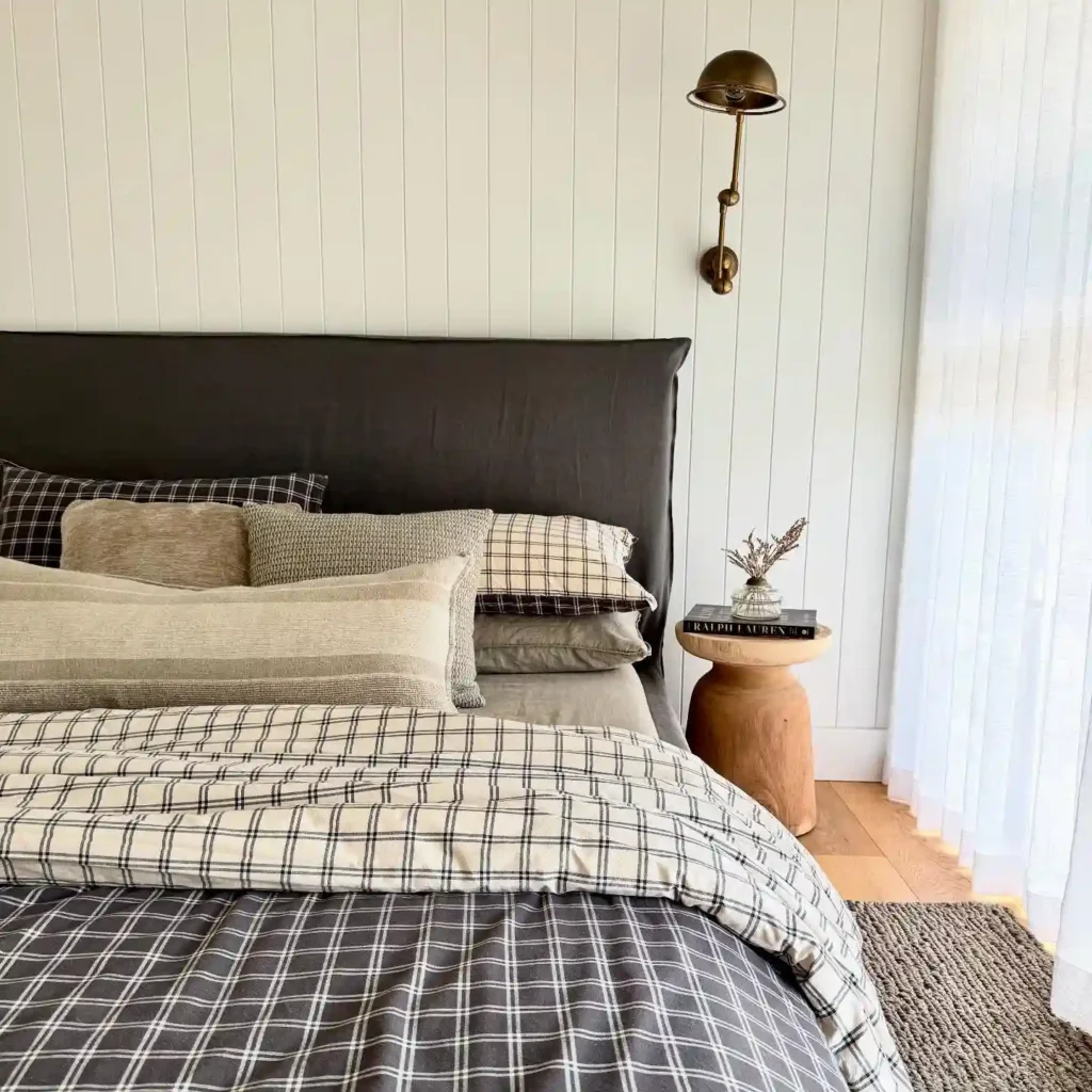 Guest bedroom bedding with plaid sheets, layered pillows, and modern neutral tones.