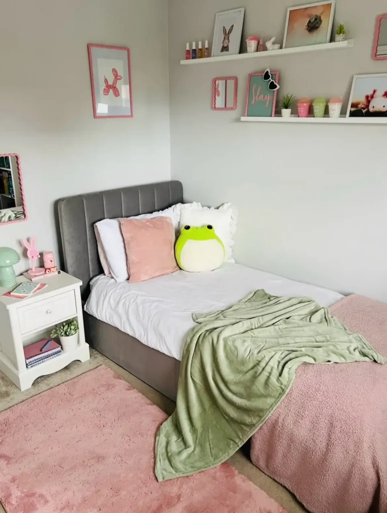 Preteen girls bedroom featuring gray bed, pastel pink rug, green blanket, and playful frog pillow decor.