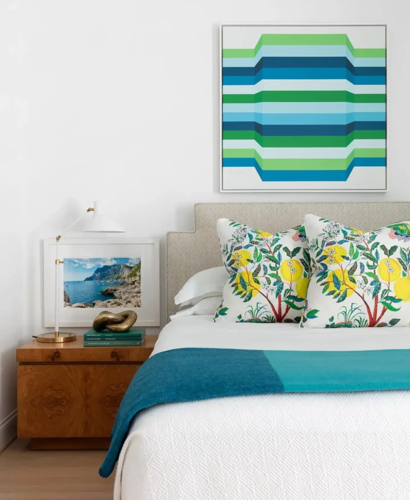 Guest bedroom with patterned pillows, bright artwork, and layered textiles.