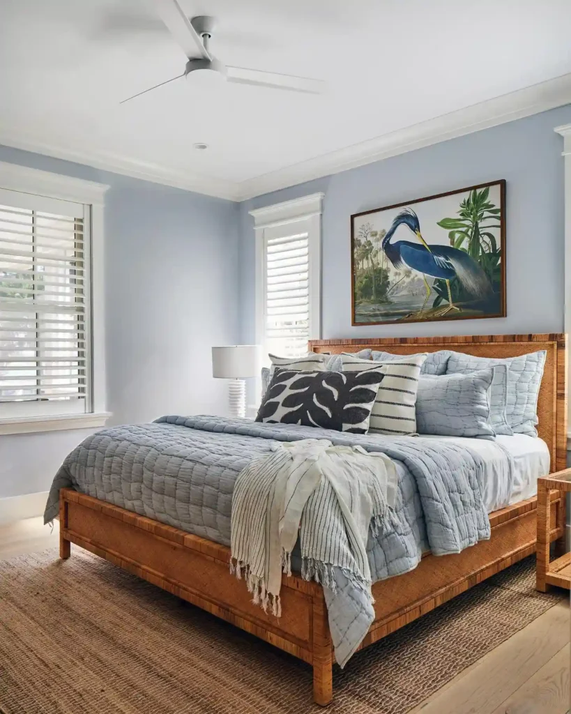 bedding with light blue quilt, striped throw, and natural wood bed.
