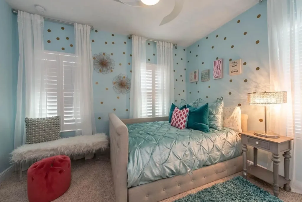 Preteen girls bedroom featuring teal bedding, turquoise walls with gold polka dots, colorful pillows, and modern lighting.
