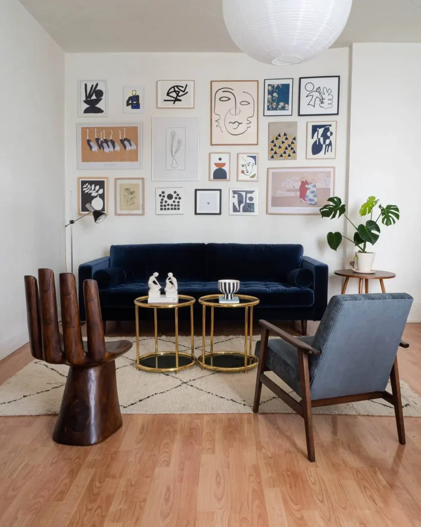 Bold gallery wall of abstract art above navy blue sofa in a modern living room for striking wall decor ideas above couch.
