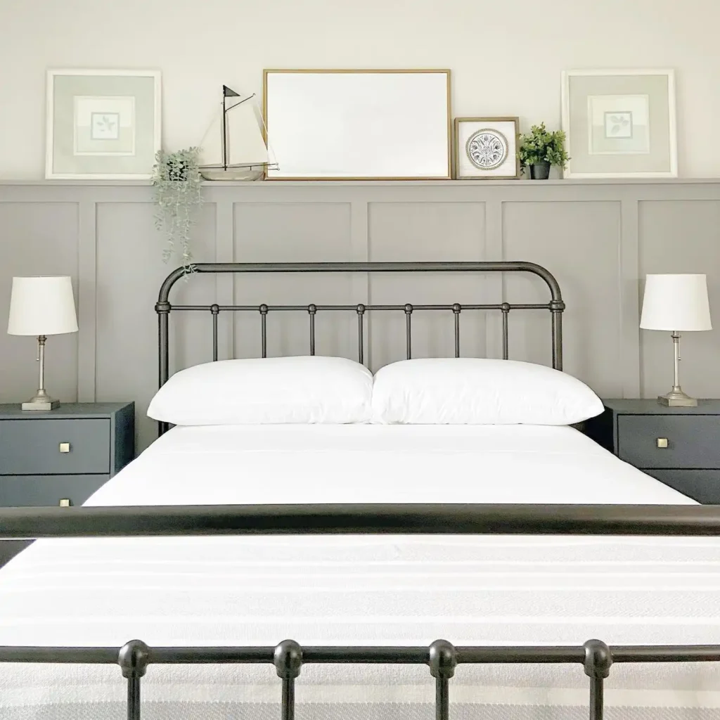 Guest bedroom with black metal bed frame, gray paneling, and simple décor.