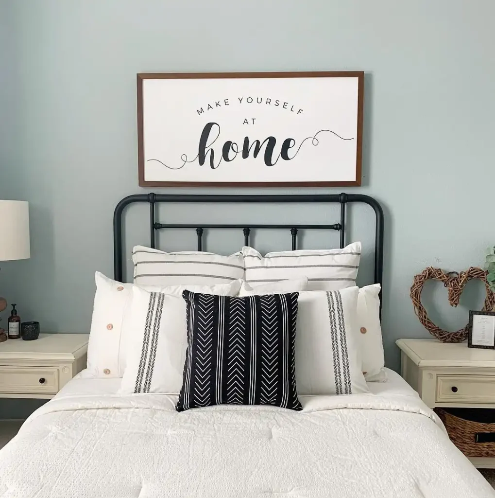 Guest bedroom with black metal bed frame, white bedding, and farmhouse décor.