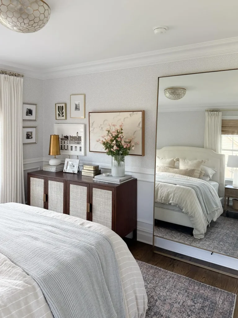 Oversized gold full length mirror in bedroom with soft neutral bedding