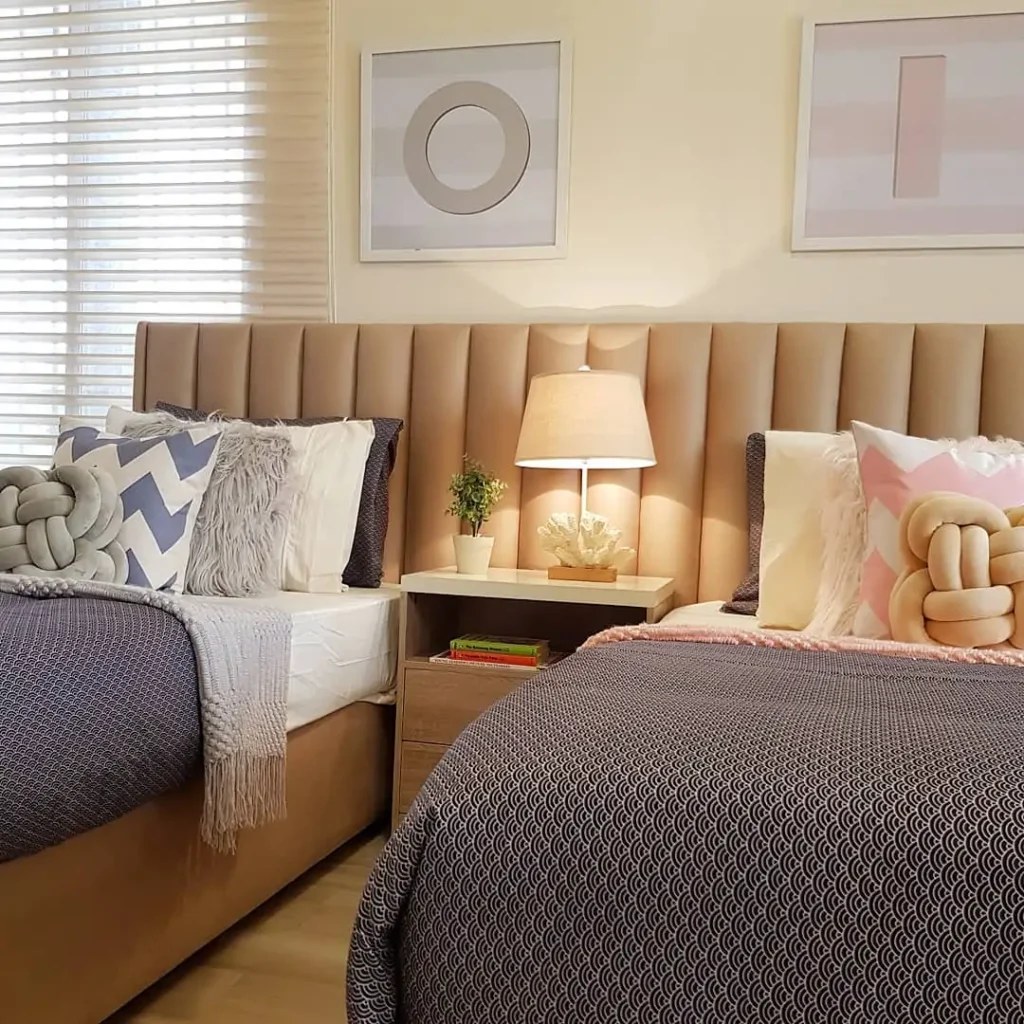 Boy and girl shared bedroom with neutral beige headboard, cozy layered bedding, and chic décor.
