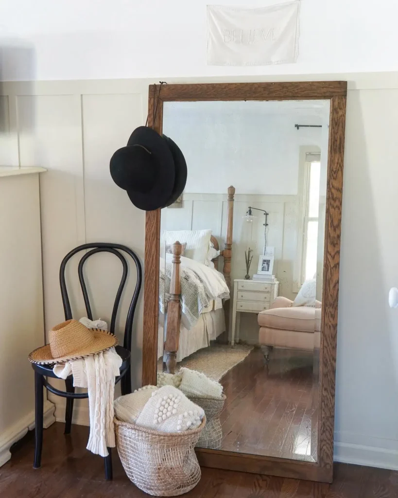 Rustic farmhouse full length mirror in bedroom with hats, chair, and woven basket
