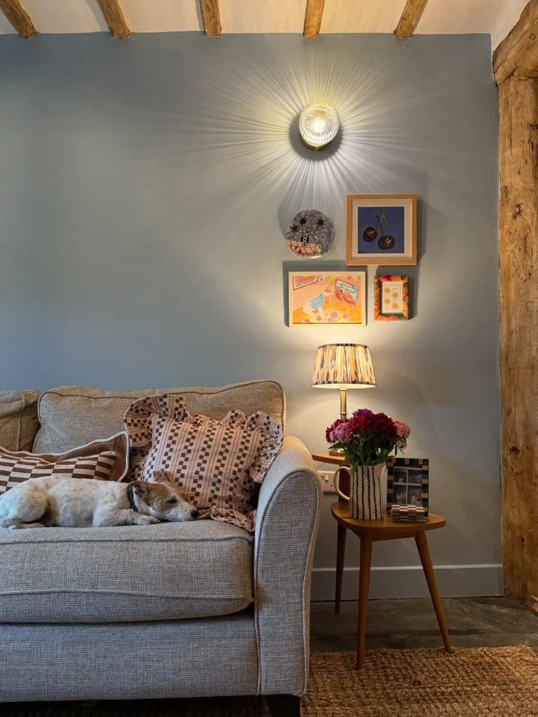 Neutral sofa with mix of small framed wall art and cozy pillows creating warm wall decor ideas above couch.
