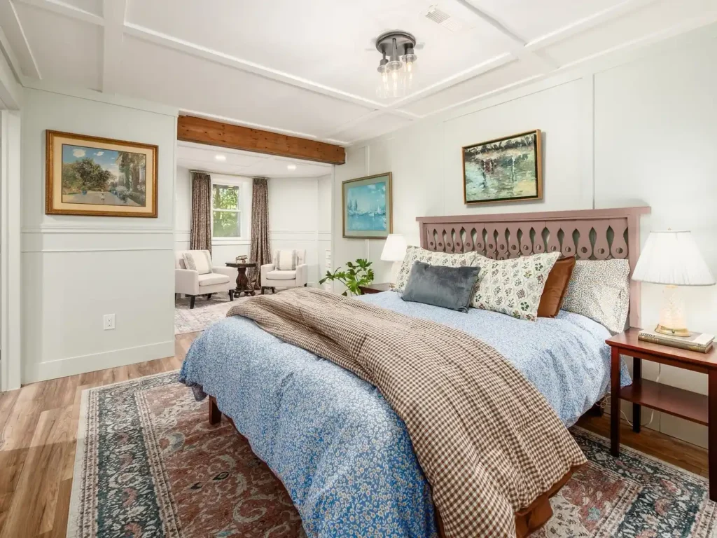 Basement bedroom with colorful bedding, patterned rugs, and eclectic artwork.
