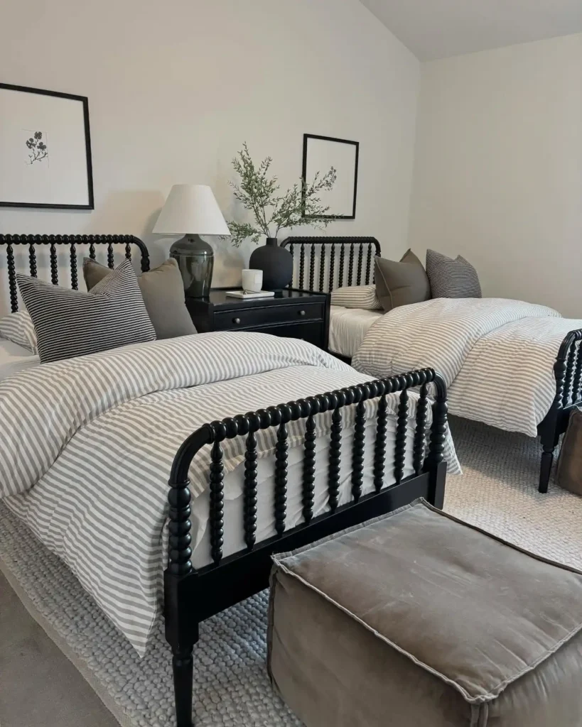 Guest bedroom with two matching beds, striped bedding, and black furniture accents.